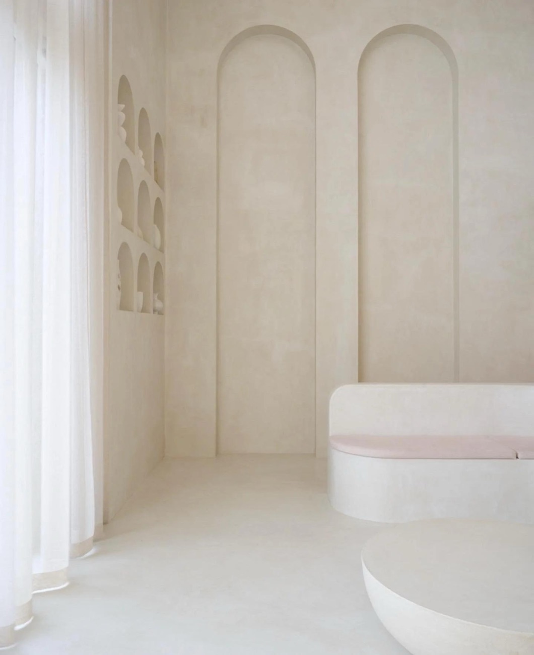 Pale plaster wall with recessed arches and a curved bench
